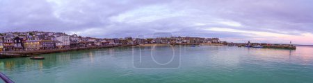 Téléchargez les photos : St Ives, Royaume-Uni - 14 octobre 2022 : Coucher de soleil panoramique sur le port, avec diverses entreprises, et le phare, à St Ives, Cornouailles, Angleterre, Royaume-Uni - en image libre de droit