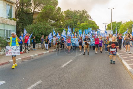 Téléchargez les photos : Haïfa, Israël - 22 juillet 2023 : Les gens défilent avec des drapeaux et divers signes. Une partie de la semaine 29 de protestation contre la révision judiciaire controversée. Haïfa, Israël - en image libre de droit