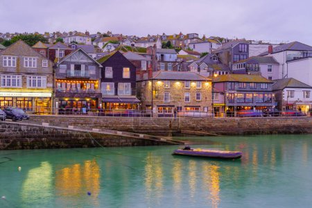 Téléchargez les photos : St Ives, Royaume-Uni - 14 octobre 2022 : Coucher de soleil sur le port, avec diverses entreprises, à St Ives, Cornouailles, Angleterre, Royaume-Uni - en image libre de droit
