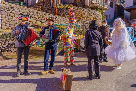 Téléchargez les photos : Valfloriana, Italy - February 26, 2022: Carnival participants costumed as bride and groom, and musicians, in the Valfloriana carnival, Trentino, Northern Italy - en image libre de droit