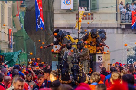 Téléchargez les photos : Ivrea, Italie - 19 février 2023 : Des groupes en pansements traditionnels et une foule avec des chapeaux rouges participent à la bataille des Oranges, dans le cadre du carnaval historique d'Ivrea, Piémont, Italie du Nord - en image libre de droit