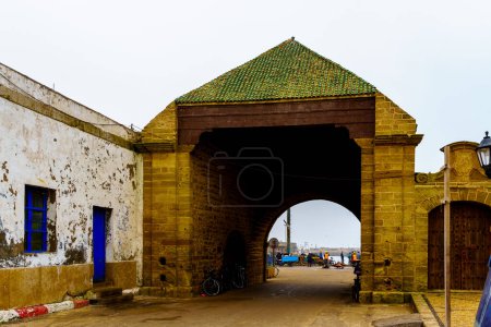 Téléchargez les photos : Essaouira, Maroc - 07 avril 2023 : Vue de la porte du port de pêche, avec les habitants et les visiteurs, à Essaouira (Mogador), Maroc - en image libre de droit
