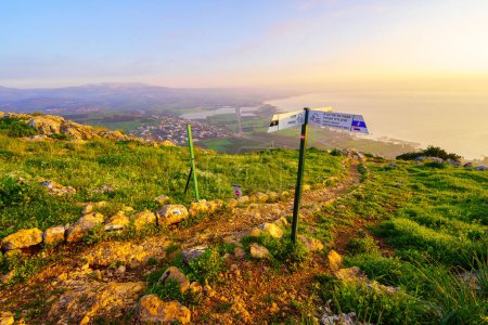 Foto de Arbel, Israel - 09 de febrero de 2024: Vista del amanecer del Mar de Galilea, y la Reserva Natural del Monte Arbel, con un sendero y una señal direccional, el norte de Israel - Imagen libre de derechos