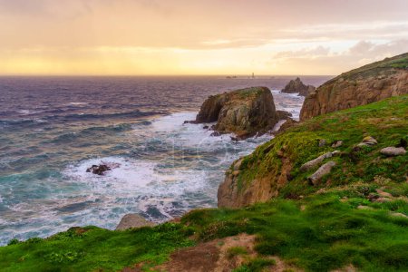 Sunset view of the Lands End coastline landscape, with the Longships Lighthouse, in Cornwall, England, UK