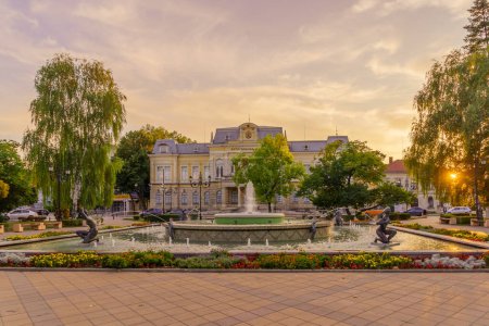 Foto de Ruse, Bulgaria - 17 de septiembre de 2023: Vista del atardecer de la antigua plaza del centro de la ciudad y el Museo Histórico, con lugareños y visitantes, en Ruse, noreste de Bulgaria - Imagen libre de derechos