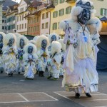 Lucerne, Switzerland - February 20, 2023: Band of musicians in costumes march in the streets, and crowd, part of the Fasnacht Carnival, in Lucerne (Luzern), Switzerland