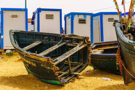 View of broken wooden boats on the beach, in the village resort Oualidia, the Atlantic coast of Morocco