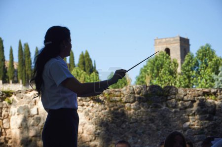 Foto de Brihuega, España - 16 de julio de 2012. Una silueta del director de orquesta de la Brihuega dirigiendo con la iglesia de San Miguel al fondo - Imagen libre de derechos