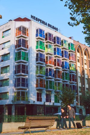Foto de 06-09-2012 Bilbao, España - Un vibrante edificio con coloridas ventanas mientras dos personas pasan por delante - Imagen libre de derechos