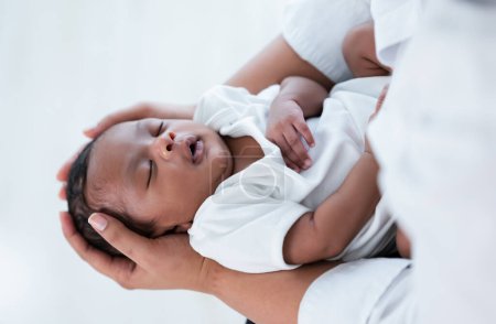 Téléchargez les photos : Vue de dessus du gros plan du nouveau-né afro-américain mignon dormant dans la main de la mère à l'hôpital. Médecine de santé. Mère noire berçant petit enfant à dormir. Nouveau-né garçon ou fille. - en image libre de droit