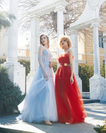 Foto de Dos mujeres vestidas de rojo se paran frente a una columna blanca. - Imagen libre de derechos