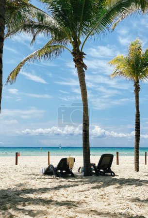Bonita playa con sillas de playa, sombrillas de paja y palmeras. vacaciones de verano en Playa del Carmen, México. Foto de alta calidad