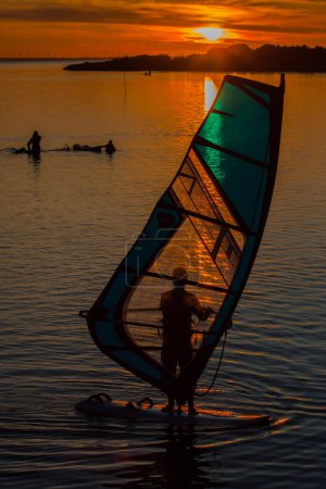 Téléchargez les photos : Planche à voile sur un lac calme au coucher du soleil, sport de vacances - en image libre de droit