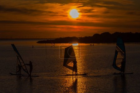 Windsurfing on a quiet lake at sunset, holiday sport
