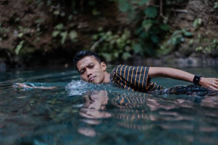 Foto de Un hombre nadando en un río de manantial muy limpio. Situado en el río Udal Gumuk, Magelang, Java Central, Indonesia. - Imagen libre de derechos