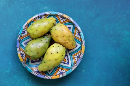 Photo for Opuntia cactus fruit close up photo. Eastern Prickly Pear on a blue decorative plate. Still life with fruit on a blue background. Food of Middle East. - Royalty Free Image