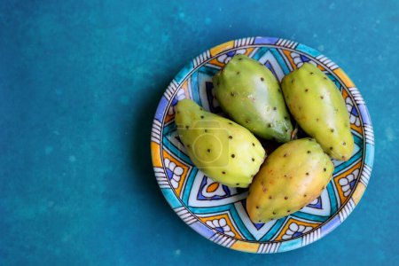 Photo for Opuntia cactus fruit close up photo. Eastern Prickly Pear on a blue decorative plate. Still life with fruit on a blue background. Food of Middle East. - Royalty Free Image