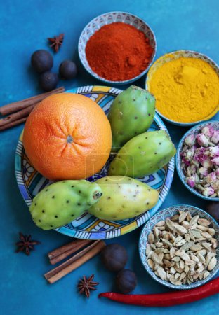 Photo for Still life with colorful fruit and spices on a table. Top view photo of grapefruit, paprika, turmeric powder, chili pepper, ginger, roses, lavender, anise and cinnamon. Blue background. - Royalty Free Image