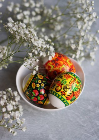 Foto de Huevos de Pascua en una mesa. Bodegón con huevos y flores blancas. Concepto de celebración Pascua. - Imagen libre de derechos