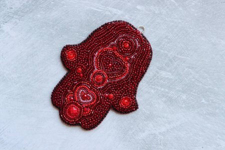 Photo for Wall hanging decoration made of red beads on a light background with copy space. Hamsa hand symbol. New Year card. - Royalty Free Image