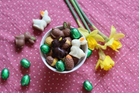 El conejito de chocolate con leche y los huevos en una mesa. Tarjeta de Pascua brillante y colorida. 