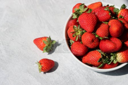 Erdbeeren in einer weißen Schüssel auf hellem Hintergrund, Ansicht von oben