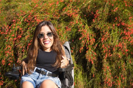 Foto de Retrato de mujer con discapacidad, movilidad reducida y pequeña estatura en una silla de ruedas eléctrica posando muy feliz en la calle en un día soleado. Concepto discapacidad, discapacidad, incapacidad, necesidades especiales - Imagen libre de derechos