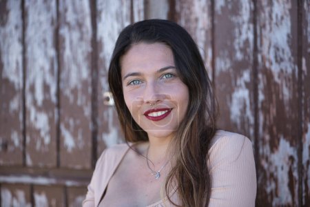 Foto de Portrait of a woman, young and attractive, blue eyes, calm and smiling on a wooden background. Concept portrait, looks, women. - Imagen libre de derechos
