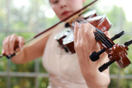 Photo for Asian female musicians playing the violin, a universal classical instrument. The concept of a classical music school. Music teacher. Violin, a classical stringed instrument. - Royalty Free Image