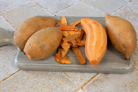 Foto de Batatas peladas en la tabla de cortar - Imagen libre de derechos