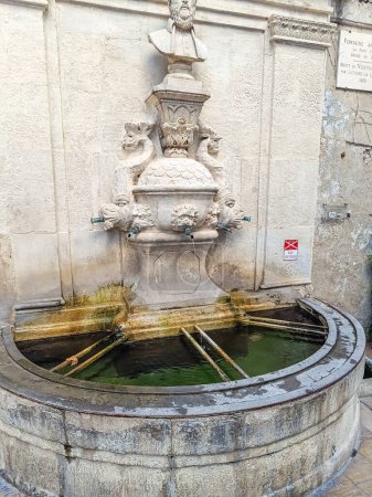 Téléchargez les photos : Fontaine avec le portrait en pierre de Nostradamus dans la ville de Saint-Rmy-de-Provence - en image libre de droit
