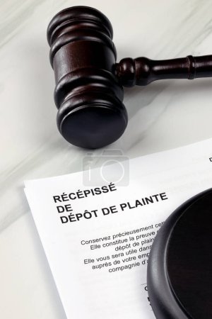 Photo for Judge's gavel and sheet of paper with "receipt of filing of complaint" written on it in French. Close-up. - Royalty Free Image