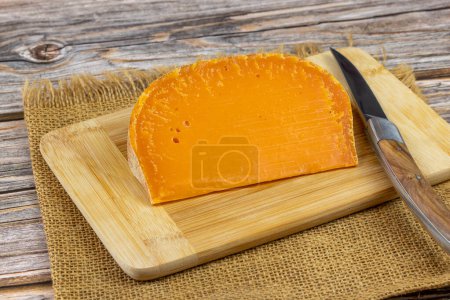rebanada de queso francés: mimolette extra viejo, primer plano, en una tabla de cortar