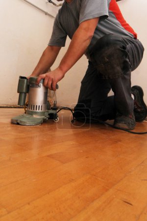 Photo for Craftsman sanding a parquet floor, working the floor in a building - Royalty Free Image