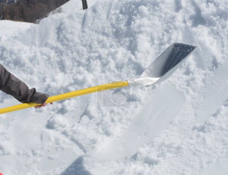 persona en la eliminación de la nieve con una pala de nieve en invierno