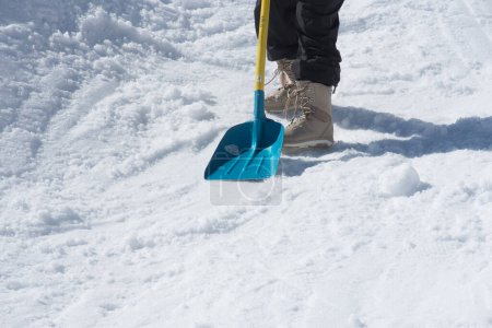 Person bei Schneeräumung im Winter mit Schneeschaufel