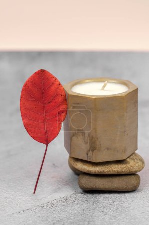 Decorative candle in a golden pot on a natural stone podium, minimal composition