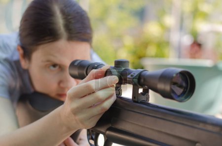 Téléchargez les photos : Un sniper femelle ajuste une vue optique tout en regardant dedans - en image libre de droit