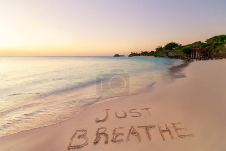Foto de Escrito a mano Solo respira en la playa de arena al atardecer, relajarse y el concepto de verano, Zanzíbar, Kendwa playa, Tanzania. - Imagen libre de derechos