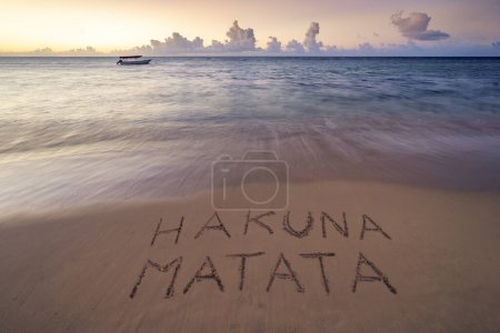 Foto de Hakuna Matata manuscrita (sin problemas) en la playa de arena al atardecer, relajarse y concepto de verano, Zanzíbar, playa africana, Tanzania. - Imagen libre de derechos
