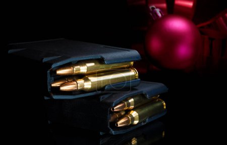 Foto de Adorno rojo de Navidad detrás de las revistas AR-15 cargadas - Imagen libre de derechos