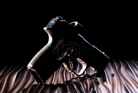 Photo for Pistol silhouette on a wavy surface with a human skull and red eyes on its grip - Royalty Free Image