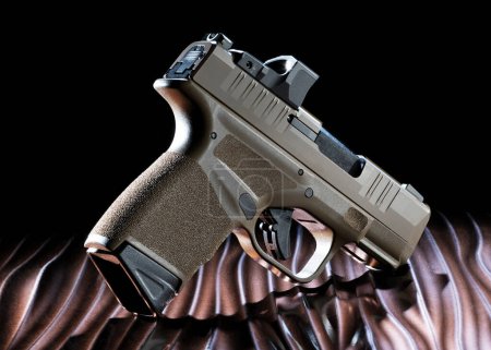 Foto de Pistola semi automática de 8 mm sobre una mesa ondulada de color bronce con fondo oscuro - Imagen libre de derechos