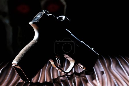 Photo for Pistol that is a ghost gun in silhouette with a glowing human skull behind - Royalty Free Image