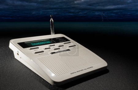 Digital hazards and weather radio that has received a thunderstorm warning with the ocean and clouds behind