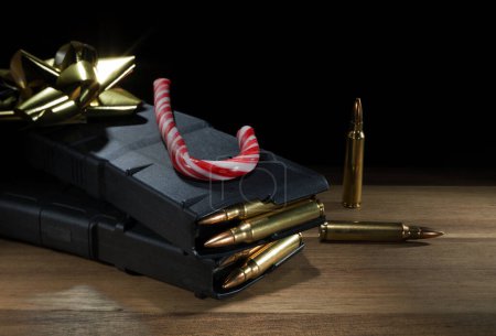 High capacity assault rifle magazines filled with ammo, along with a candy cane and gold bow with a black background with plenty of space for text.
