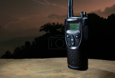 Handheld two way radio with a display showing a weather alert has been issued