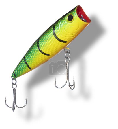 Shadow below a topwater artificial fishing bait with green, yellow and red color with dual treble hooks rising toward the surface.