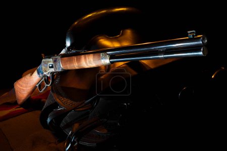 Dark background behind the saddle and lever action rifle with orange rim lighting.