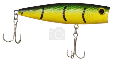 Lure used on topwater for fishing with yellow and green color and a pair of shiny treble hooks. 